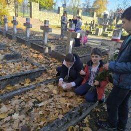 Uczniowie klas I-III zapalający znicze na mogiłach