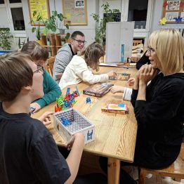 Dziewczęta z panią układają wieżę z krzeseł - Mistakos. 