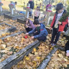 Uczniowie klas I-III zapalający znicze na mogiłach