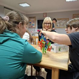 Dziewczęta z panią układają wieżę z krzeseł - Mistakos. 
