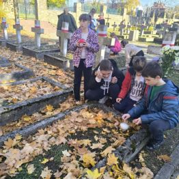 Uczniowie klas I-III zapalający znicze na mogiłach