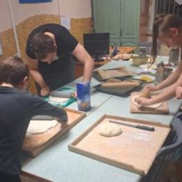 Wychowankowie wyrabiają ciasto na pizzę.