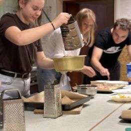 Wychowanki nakładają produkty na ciasto.