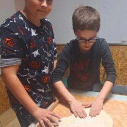 Wychowankowie przygotowują ciasto do pizzy.