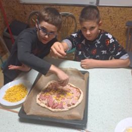 Wychowankowie nakładają  produkty na ciasto.