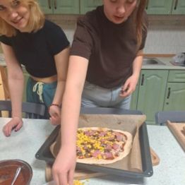 Dziewczynki nakładają produkty na ciasto.