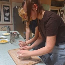 Dziewczynki przygotowują ciasto na pizzę.