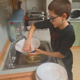 Chłopiec myje naczynia.