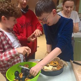 Wychowankowie przygotowują placek ze śliwkami.