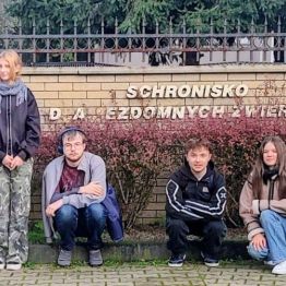 Wychowankowie i wychowawcy przed bramą wejściową do „Schroniska dla Bezdomnych Zwierząt”.