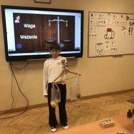 Uczennica klasy 3a eksponuje własnoręcznie wykonaną wagę.