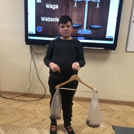Uczeń klasy 1 b eksponuje własnoręcznie wykonaną wagę.
