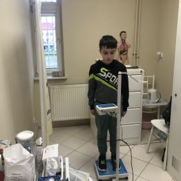 Uczeń klasy 1b podczas ważenia w gabinecie pielęgniarki.