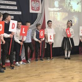 najmłodsi tańczą na scenie, w ręku trzymają rekwizyty