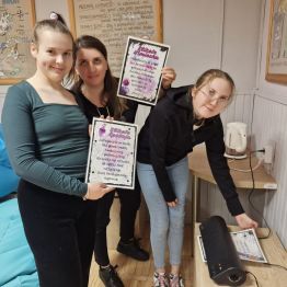 Wychowankowie wraz z wychowawcą laminują dekoracje Andrzejkowe