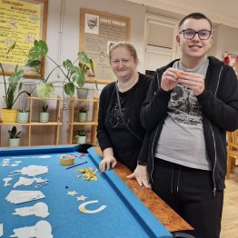 Wychowawca z wychowankiem przygotowują elementy na fotobudkę Andrzejkową