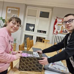 Wychowankowie przyklejają elementy na pudełko Andrzejkowe 