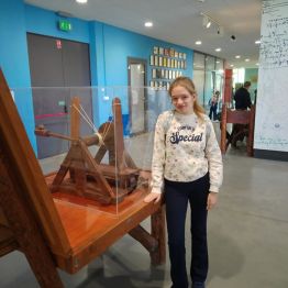 Dziewczynka stoi przy stole z eksponatem.