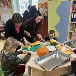 Wychowawcy z dziećmi przygotowują warzywa na zupę dyniową. 