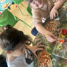 Dzieci wykonują pracę plastyczną - dynią z kartonu i pestek. 