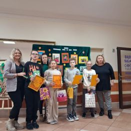 Zwycięzcy konkursu wraz z panią kierownik i n-lami na tle tablicy konkursowej.