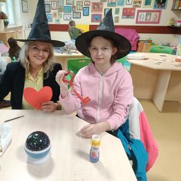 Uczennica wraz z n-lką siedzą przy stole z wróżbami.