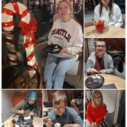 Wychowankowie spędzają czas w przytulnej kawiarni, siedząc przy stolikach z kawą i deserami w zimowo-świątecznej atmosferze.