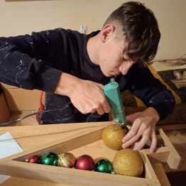 chłopiec przykleja klejem bombki na choince