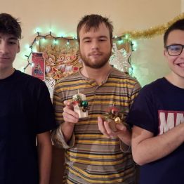 wychowankowie pokazują choinki i świece przygotowane na kiermasz