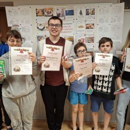 Dzieci z dyplomami i słodkimi upominkami.