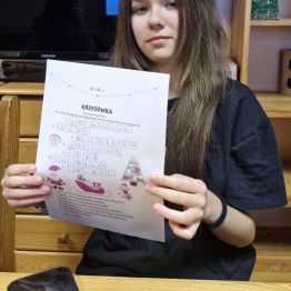 Wychowanka pokazuje rozwiązaną krzyżówkę o tematyce świątecznej. 