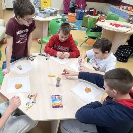 Grupa uczniów dekoruje pierniki. 