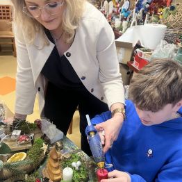 Wychowawca z uczniem podczas pracy nad kompozycja bożonarodzeniowa. 