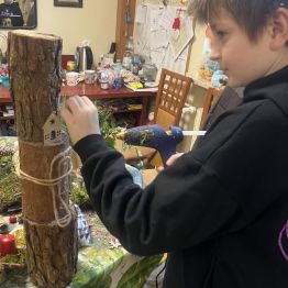 Uczeń dekoruje kompozycję bożonarodzeniową. 