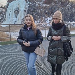 Pani pedagog z wychowankami spacerują wzdłuż alejki. W tle lodospad.