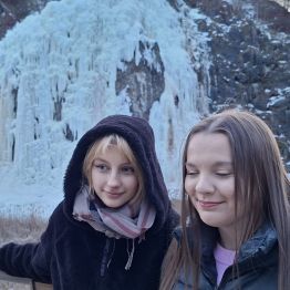 Dwie dziewczynki na tle pięknego lodospadu.