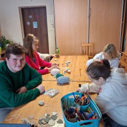 Grupa uczniów przygotowuje serca z włóczki.