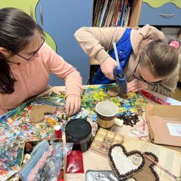 Dziewczynki przyklejają ziarna kawy.