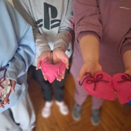 Uczniowie prezentują wykonane przez siebie serduszka z materiału. 