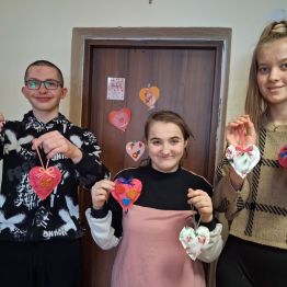 Uczniowie prezentują samodzielnie wykonane materiałowe serduszka. 