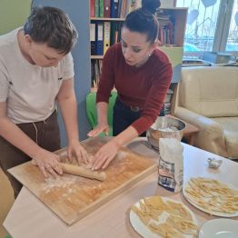 Wychowawca instruuje ucznia w jaki sposób należy wałkować ciasto. 