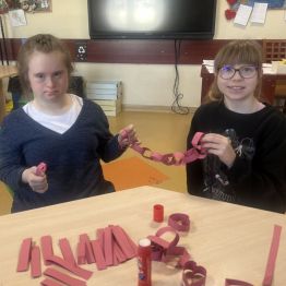 Kasia i Emilka prezentują papierowy łańcuch z serc. 