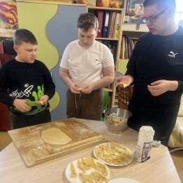 Uczniowie podczas zawijania ciasta na faworki. 