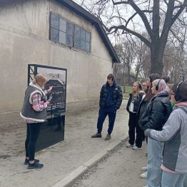 pani przewodnik pokazuje uczniom na gablocie widok baraku