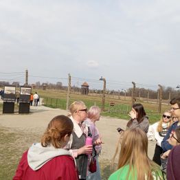 uczniowie wraz z panią przewodnik zwiedzają Auschwitz