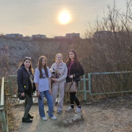 Wychowanki z wychowawcami pozują do zdjęcia przy zachodzie słońca.