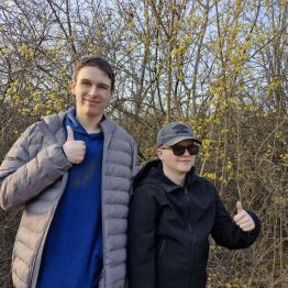 Wychowankowie pozują do zdjęcia na tle rozkwitającego drzewa- zwracanie uwagi na zwiastuny wiosny.