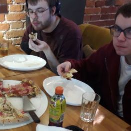 chłopcy jedzą pizzę w restauracji