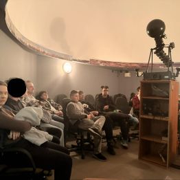 dzieci siedzą w Planetarium czekają na seans