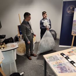 Chłopiec podnosi worek ze zniszczonymi pieniędzmi.